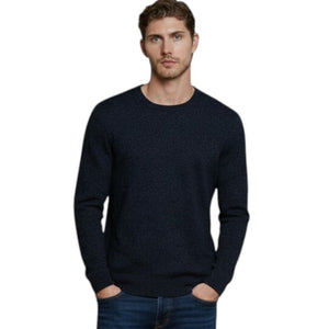 A man with short brown hair stands with his hands in his pockets against a white background, wearing the AUTUMN CASHMERE - Cashmere Basic Crew Neck with Rib Bottom in Midnight and blue jeans.