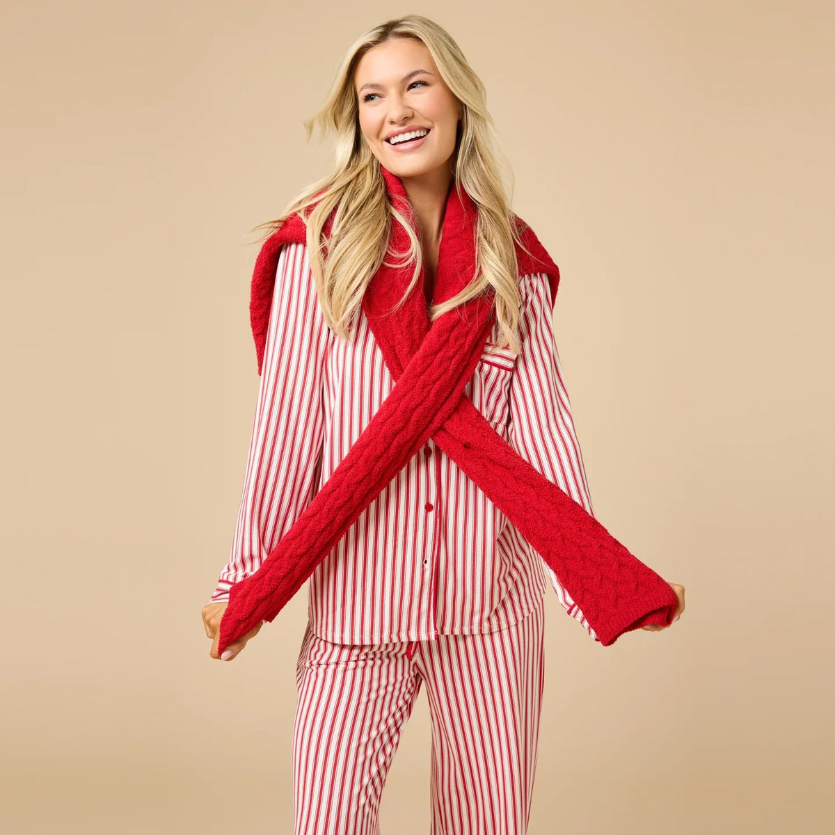 A woman wears the SOFTIES ARIA SLIM NOTCH COLLAR PJ SET, featuring a long-sleeved button-down top and matching wide-leg pants in red and white vertical stripes with red piping details.