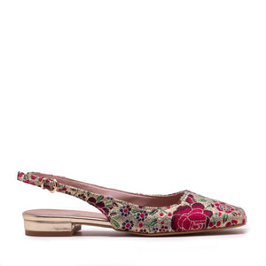 Side view of the MICHELE LOPRIORE - SQUARED SLINGBACK, a single slingback flat shoe with a colorful floral pattern featuring shades of pink, red, green, and blue. This Italian-made shoe has a closed pointed toe, an adjustable gold buckle on the ankle strap, and a small gold heel. It boasts a genuine leather sole for added comfort and durability courtesy of the brand MICHELE LOPRIORE.