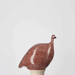 The LES CERAMIQUES DE LUSSAN - PETITE CERAMIC FRENCH GUINEA IN BORDEAUX SPOTTED WHITE from LES CERAMIQUES DE LUSSAN features a rounded ceramic bird adorned with bordeaux and white spotted patterns, reminiscent of French guinea hens, displayed against a plain white background.