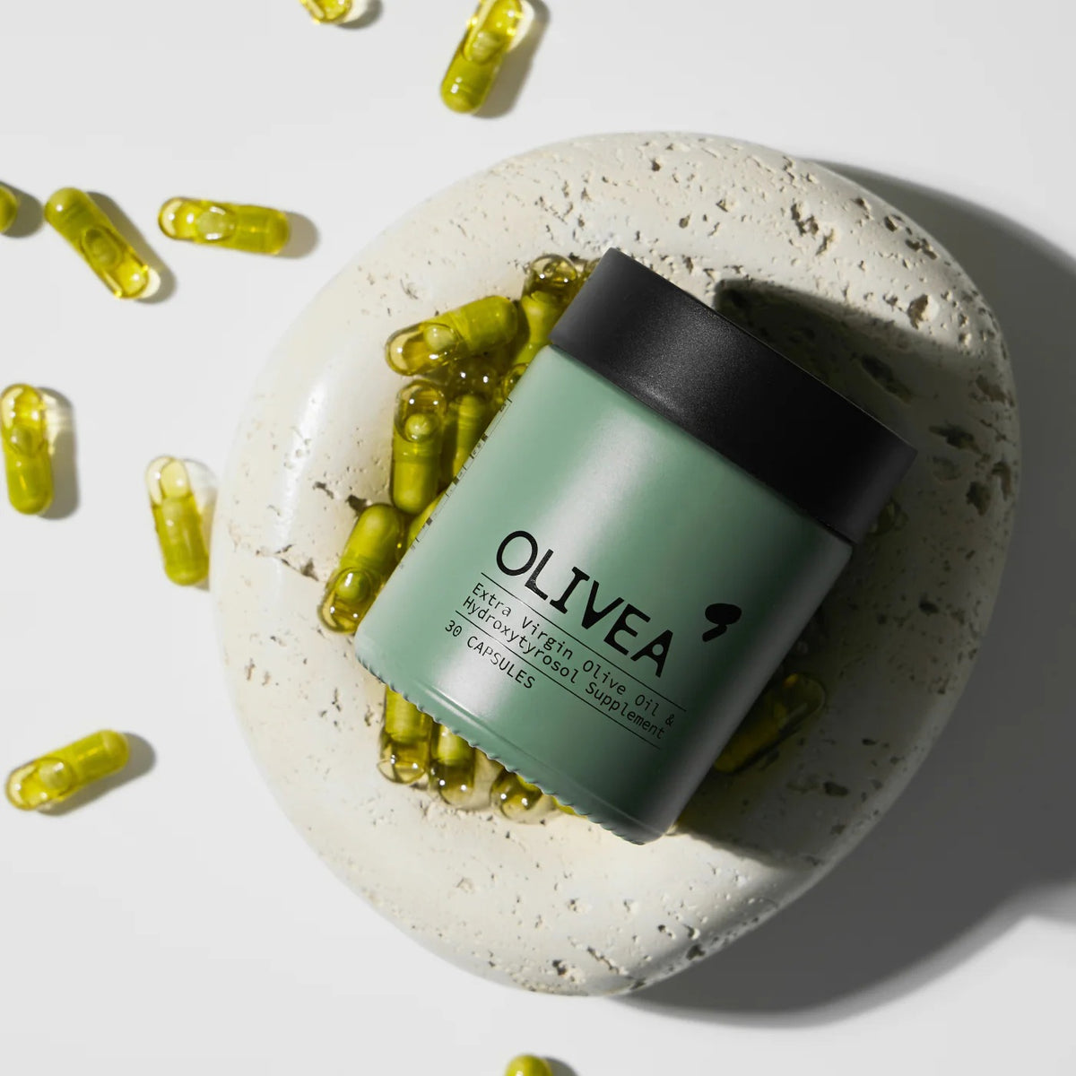 Four yellow capsules on a white surface, with the text “More potent than an olive oil shot” above them—each OLIVEA EVOO &amp; HYDROXYTYROSOL SUPPLEMENT delivers a concentrated 20 mg dose of olive polyphenols and hydroxytyrosol, powerful compounds from high-phenolic olive oil by OLIVEA.