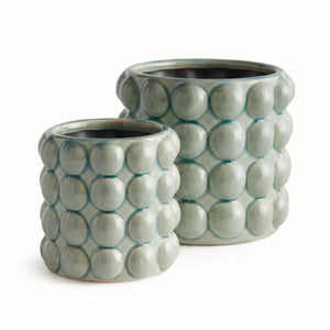 The NAPA HOME AND GARDEN - VALENCIA POT, SMALL by NAPA HOME AND GARDEN is a light green contemporary planter with a glossy seafoam glaze and a textured surface featuring raised circular bumps arranged in a grid pattern.