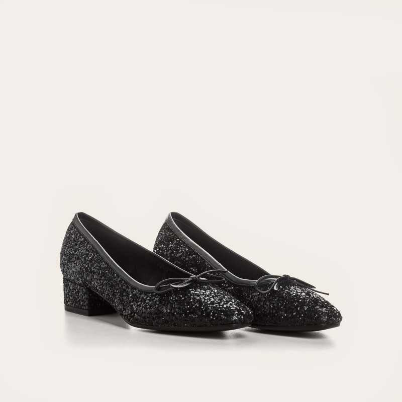 A single REQINS - FETICHE GLITTER HEELED BALLERINA shoe, black and covered in glitter, viewed from above with a small bow on the toe and &quot;REQINS&quot; on the insole—perfect elegant party shoes.
