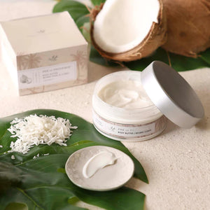 A clear plastic jar with a silver lid containing European Soaps, LLC Body Butter - Coconut, enriched with shea butter. The label displays "Coconut" and "Body Butter | Beurre Corps," along with an illustration of coconut trees. The jar holds 6.7 fl oz (200 mL) of body butter to moisturize your skin.
