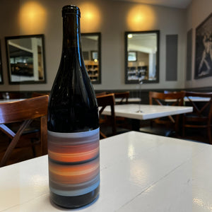 A bottle of TIMEPLACE PINOT NOIR 2023 by WINE: ADVINTAGE, featuring a label adorned with horizontal stripes in orange, red, gray, and white tones, showcased against a plain white background—an elegant depiction of this Santa Barbara County Pinot Noir.