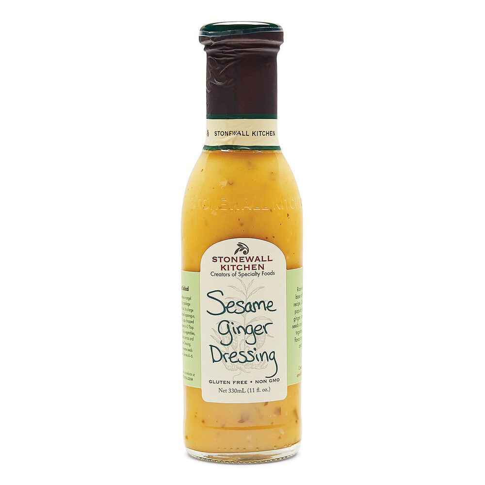 A bottle of STONEWALL KITCHEN - SESAME GINGER DRESSING from Stonewall Kitchen stands against a white background. The label indicates it is gluten-free and non-GMO. Perfect for an Asian-inspired recipe, this salad dressing boasts a light brown hue with visible sesame seeds and hints of rice wine vinegar.