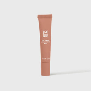 A close-up shows glossy, peachy-pink lips enhanced with U BEAUTY’s PLASMA LIP COMPOUND IN FAWN, gently touched by a finger.