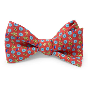 The BIRD DOG BAY PETER-BLAIR Sunscreen Silk Bow Tie in Red is laid flat on a white background, showcasing its handmade design with a repeating pattern of small blue and yellow floral-like shapes on luxurious red silk. The adjustable neck sizing guarantees a perfect fit for any occasion.