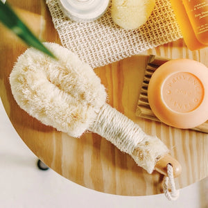 Introducing the BAUDELAIRE - SISAL 9” BODY BRUSH by BAUDELAIRE—a natural sisal body brush featuring a sturdy wooden handle, convenient rope loop, and dense pale bristles. Ideal for exfoliating and dry brushing, this brush is finished with a tag that reads “Baudelaire Sisal Brush.”.