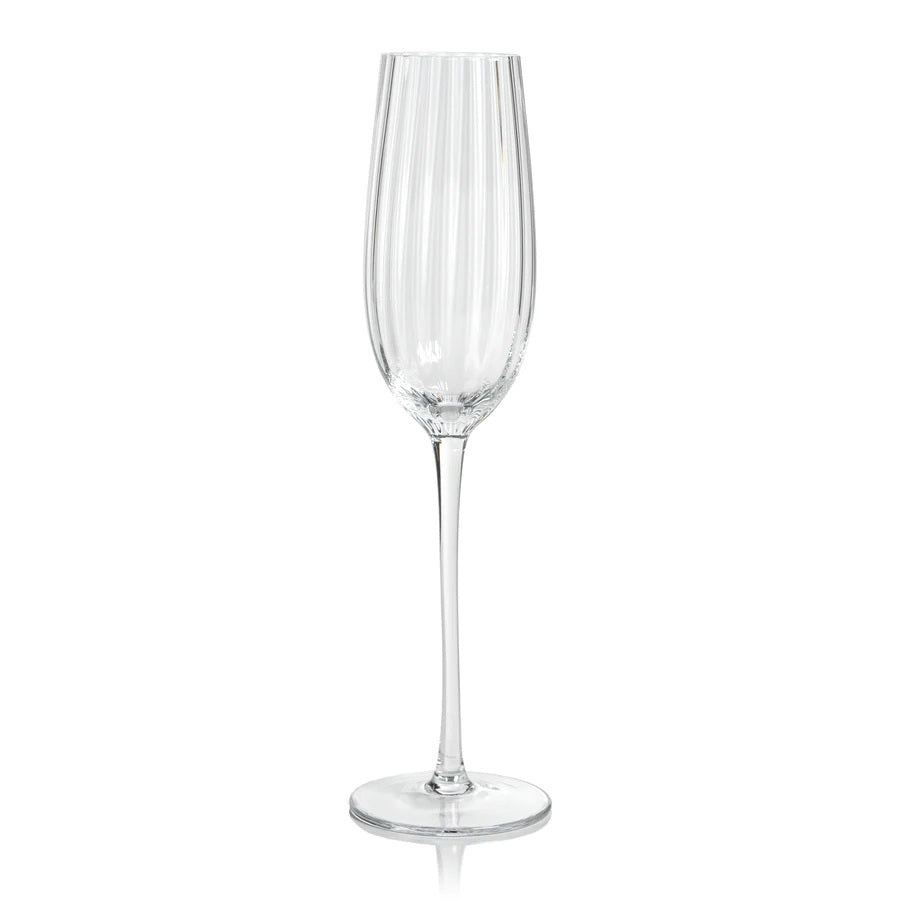 The MADELEINE OPTIC CHAMPAGNE FLUTE by ZODAX is a tall and slender clear crystal glass adorned with vertical grooves extending from the rim to the stem, which rests on a flat, round base. The empty flute showcases a polished, reflective finish that elevates its elegance, making it perfect for special occasions and toasting celebrations.