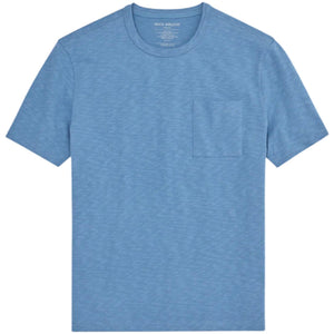 A man with short curly hair wears the MACK WELDON Heavyweight Slub Cotton Pocket T-Shirt in Dean Blue with dark pants, standing against a plain white background.