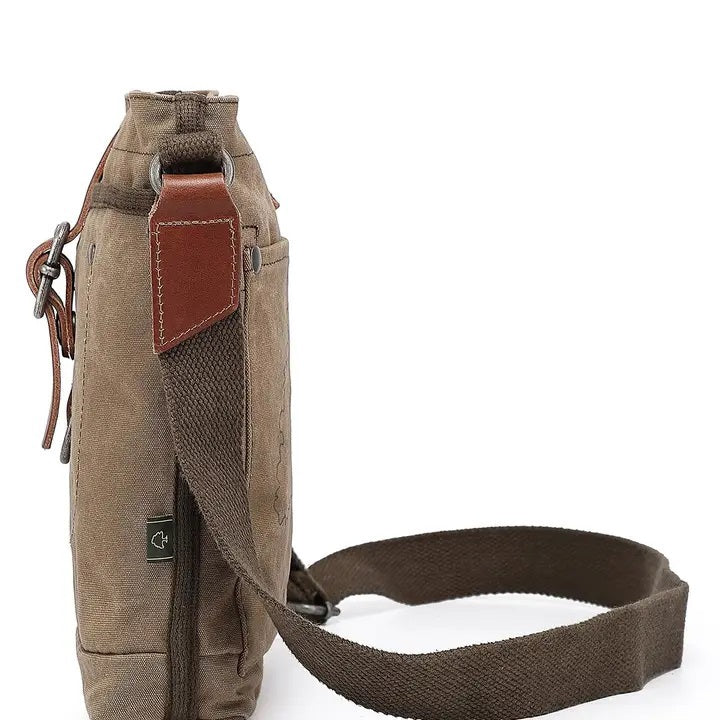 The TSD BRAND - FOREST ZIP CROSSBODY BAG IN OLIVE is a military-inspired khaki canvas bag with a front pocket, brown adjustable strap, decorative leather buckle, metal rivets, and textured shoulder strap for style and durability.
