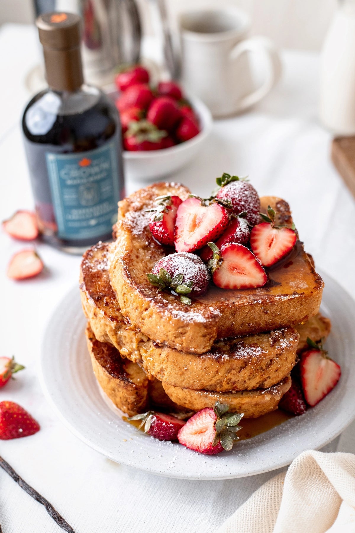 A glass bottle of CROWN MAPLE - VAINILLA INFUSED ORGANIC MAPLE SYRUP by CROWN MAPLE, featuring a gold cap and a blue label with product details and certifications—ideal as an organic maple syrup for baking or enhancing your favorite recipes with the rich flavor of vanilla.