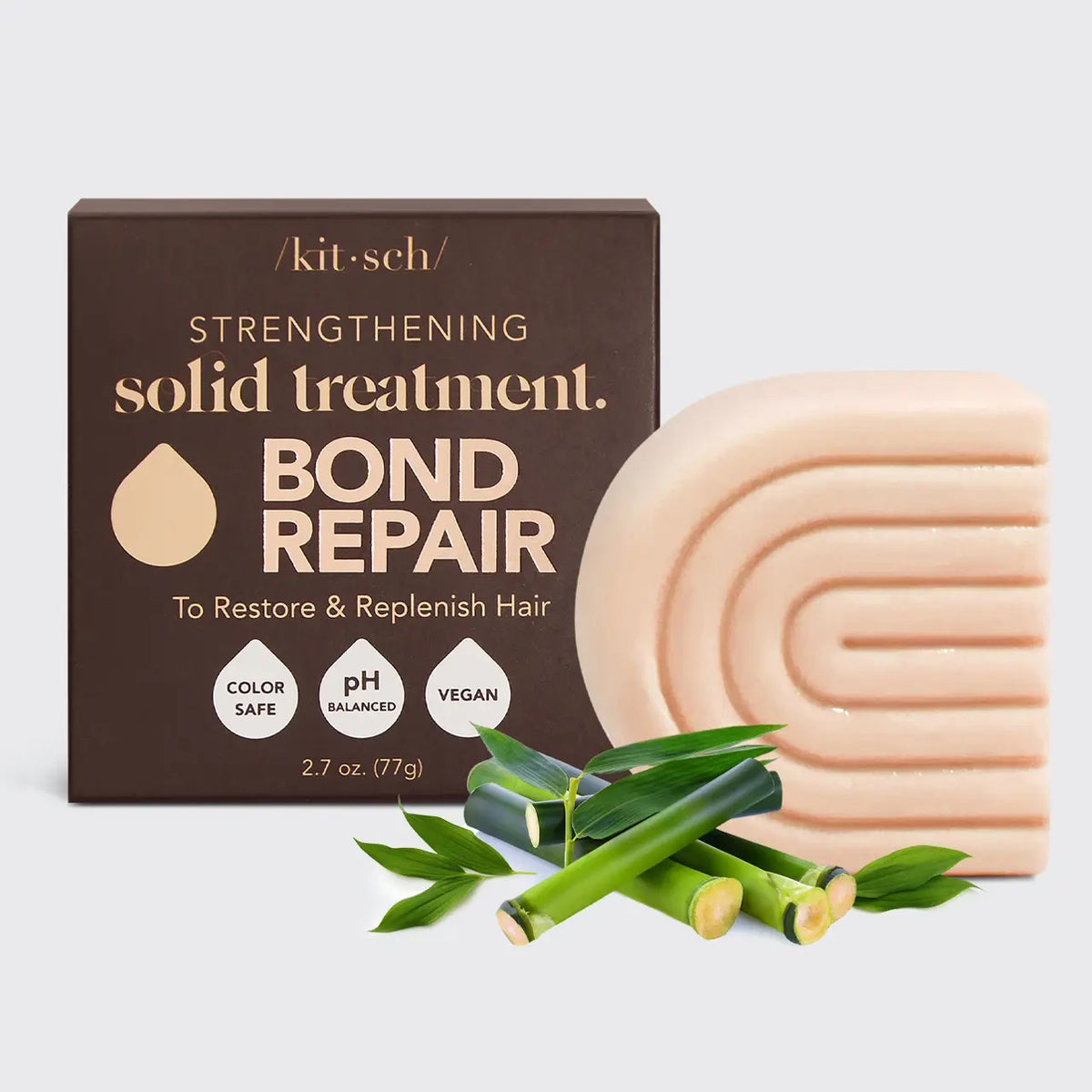 A KITSCH - STRENGTHENING BOND REPAIR SOLID HAIR MASK BAR rests by its brown box with bamboo stems, highlighting its vegan keratin formula for glass hair that's color safe and pH balanced.