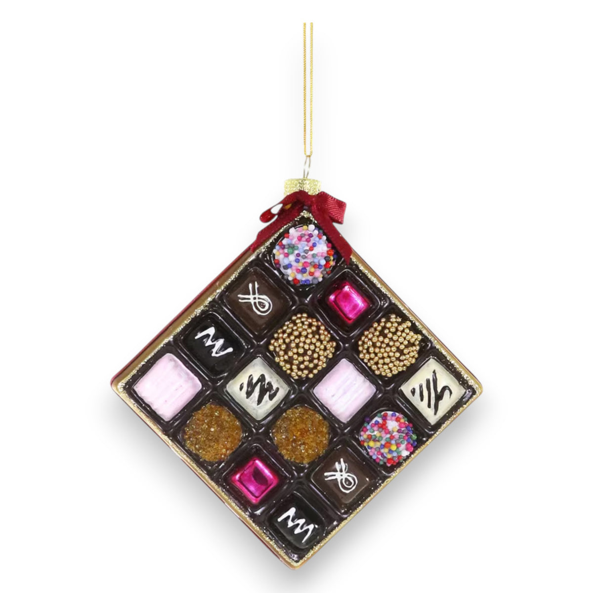 The CODY FOSTER BOX OF CHOCOLATES ORNAMENT is a square hanging décor with a gold string and red bow, featuring rows of colorful, decorated chocolates—perfect for collectors and design enthusiasts.