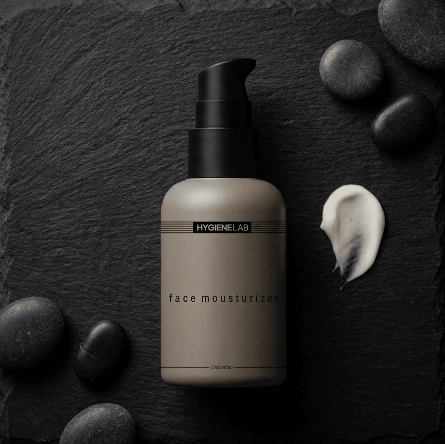 A beige bottle with a black pump, labeled “HYGIENELAB - FACE MOISTURIZER, UNSCENTED,” sits against a white background; this product from HYGIENELAB is formulated with ceramides and hyaluronic acid to provide optimal hydration.