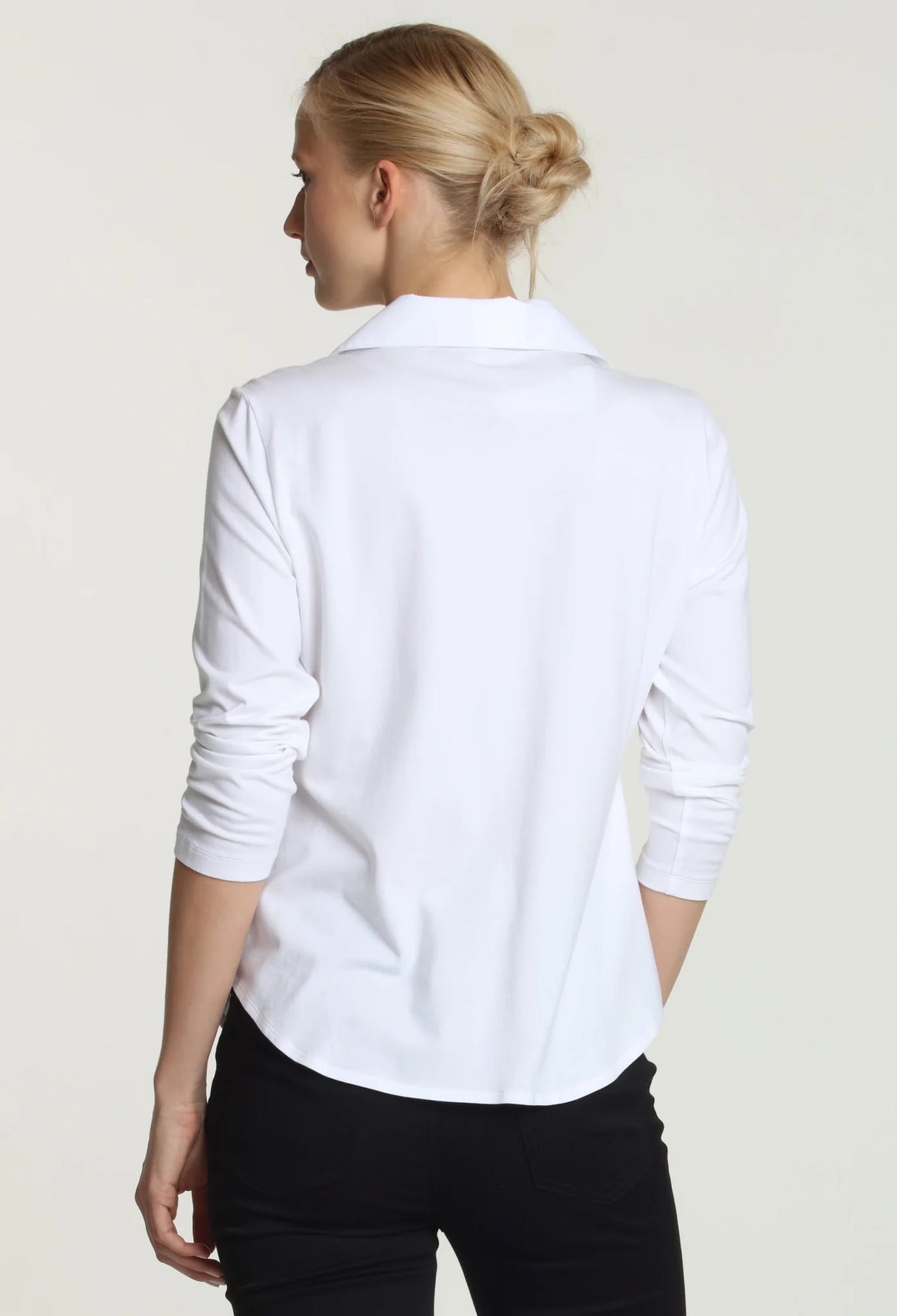 A person with short blonde hair wearing the HINSON WU - DONNA 3/4 SLEEVE TOP stands against a plain light gray background. They are looking directly at the camera with a neutral expression, their arms resting at their sides.