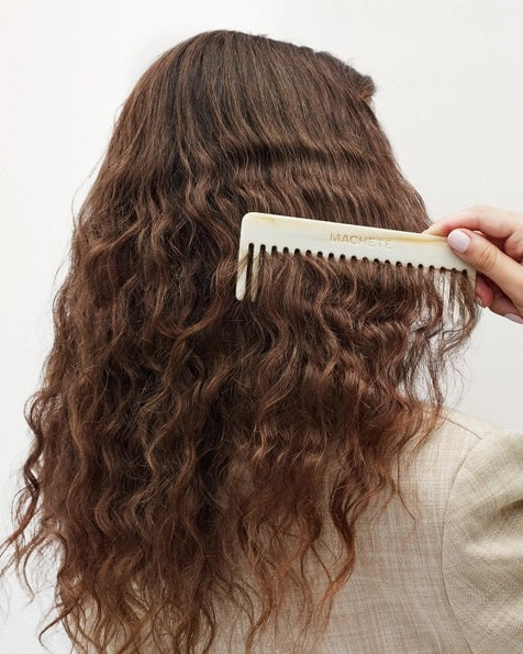 The MACHETE - No. 2 Comb in Ivory, crafted from marbled Italian acetate in a cream hue and featuring wide-set teeth, is displayed vertically against a plain white background.