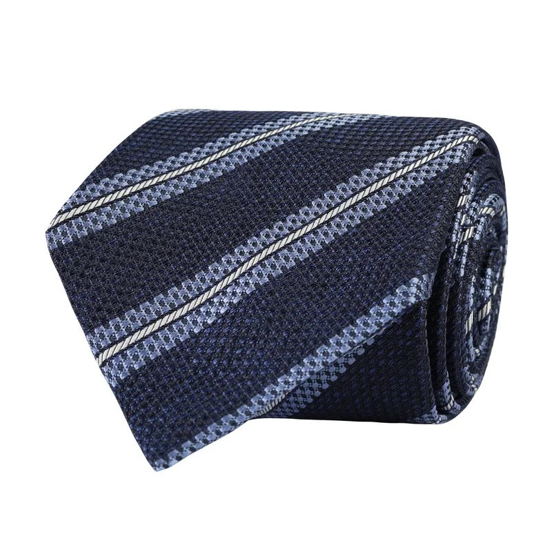 The AMANDA CHRISTENSEN - Striped Jacquard Woven Silk Tie in Navy Melange features diagonal light blue and white stripes on a textured navy silk background, making it an ideal choice for elevating your business attire and adding a sophisticated touch to any men’s accessories collection.