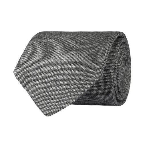 Close-up of the AMANDA CHRISTENSEN - JACQUARD LINEN TIE IN GREY, featuring a textured jacquard linen fabric in grey and a black label that reads “Amanda Christensen, Sweden 1885.” Displayed flat to reveal both the front and back, this elegant tie is a timeless staple from AMANDA CHRISTENSEN’s classic men’s accessories collection.