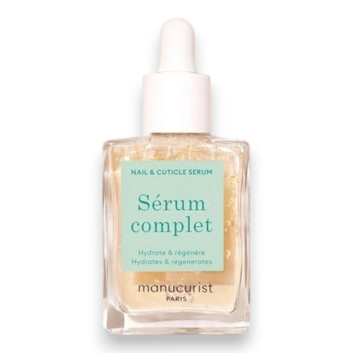 A square glass bottle labeled “MANUCURIST - COMPLETE SERUM” by MANUCURIST INC is displayed, featuring a dropper cap. The dropper, filled with a clear liquid dotted with tiny bubbles, rests beside the bottle—ideal for nourishing damaged nails and delivering essential hydration to cuticles. The scene is set against a soft beige background.