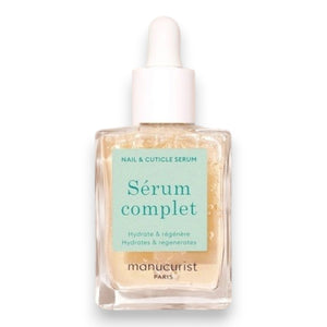 A square glass bottle labeled “MANUCURIST - COMPLETE SERUM” by MANUCURIST INC is displayed, featuring a dropper cap. The dropper, filled with a clear liquid dotted with tiny bubbles, rests beside the bottle—ideal for nourishing damaged nails and delivering essential hydration to cuticles. The scene is set against a soft beige background.