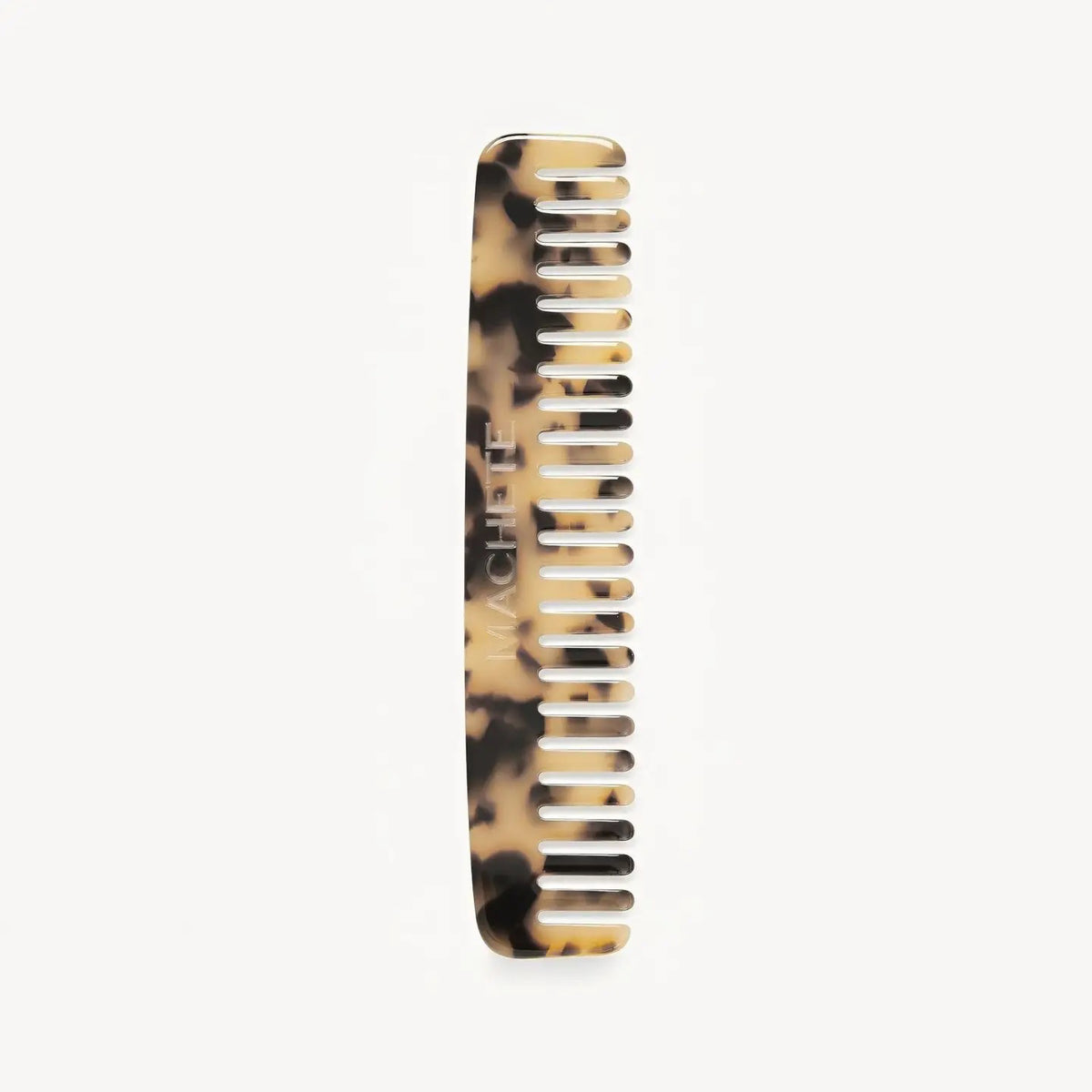 The MACHETE No. 3 Comb in Blonde Tortoise, made from Italian acetate with "MACHETE" engraved on the side, stands vertically against a white background—a chic travel-friendly wide-tooth comb essential.
