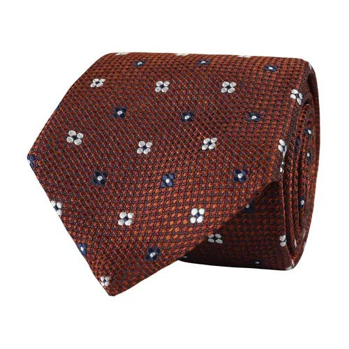The AMANDA CHRISTENSEN - FLORAL JACQUARD WOVEN SILK TIE IN RUST MELANGE showcases a refined textured pattern in rust mélange silk, detailed with small blue and white floral motifs—an elegant men’s accessory from AMANDA CHRISTENSEN, ideal for elevating your business attire.