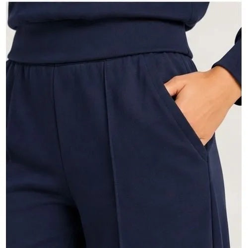 A woman wears a SOFTIES - DREAMTECH BOAT NECK WITH PINTUCK PANT SET in olive green, featuring a long-sleeve boat neck top and matching wide-leg pintuck pants.