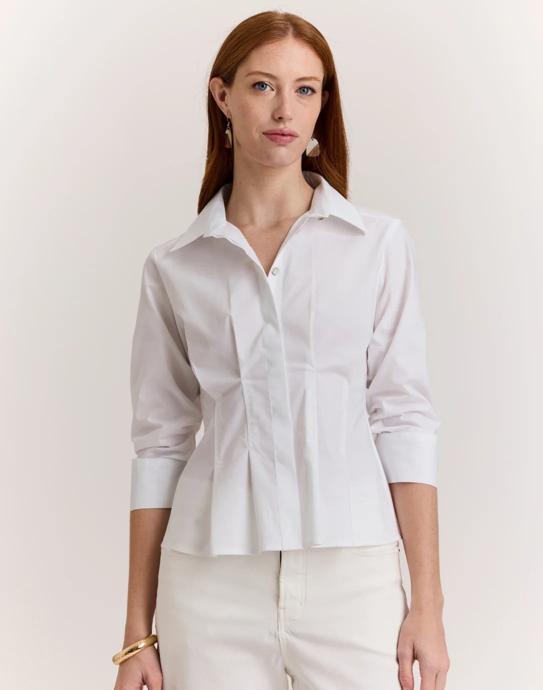 A woman with long red hair wears the HINSON WU - MARTINA 3/4 SLEEVE STRETCH POLISHED COTTON SHIRT IN WHITE, paired with matching white pants, standing against a plain light background.