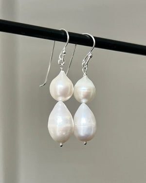 The ANN LIGHTFOOT - DOUBLE DROPLET FRESHWATER PEARL EARRINGS feature teardrop-shaped white pearls on sterling silver hooks, shown against a plain white background.