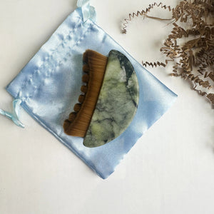 The SMILE BOUTIQUES LYMPHATIC BRUSH WITH NATURAL JADE is a crescent-shaped massage tool featuring soft brown bristles on one side, ideal for facial or scalp massage and perfect for enhancing your skincare routine, displayed against a white background.