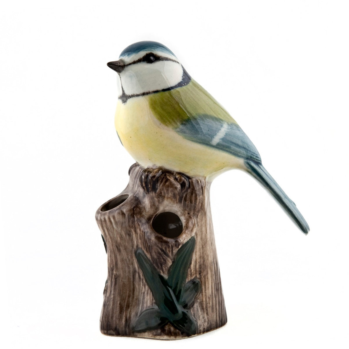 The QUAIL CERAMICS - BLUE TIT BIRD BUD VASE by QUAIL DESIGNS features a handpainted blue tit with yellow, blue, and green details perched on a brown tree stump with green leaves against a white stoneware background.