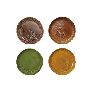 Four CREATIVE COOP DEBOSSED STONEWARE SCALLOPED PLATES with botanical designs and scalloped edges in brown, orange, green, and yellow, arranged in a square on a white background.