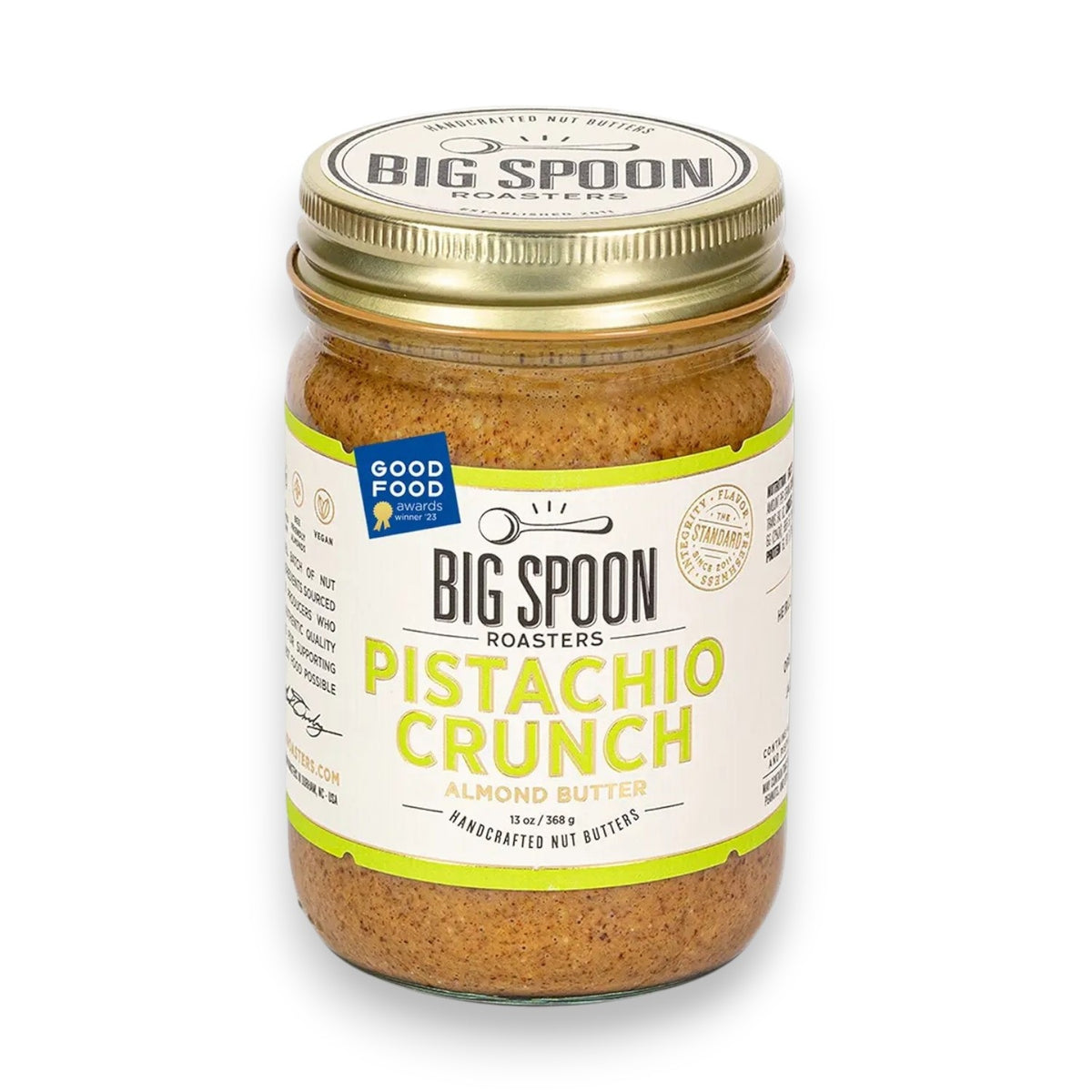A clear glass jar of BIG SPOON ROASTERS - PISTACHIO &amp; ALMOND CRUNCH NUT BUTTER, sealed with a gold lid and a white label with green and yellow text. The nut butter is made from heirloom mission almonds by BIG SPOON ROASTERS.