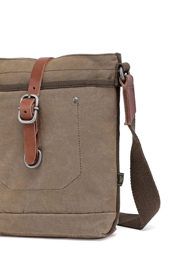 The TSD BRAND - FOREST ZIP CROSSBODY BAG IN OLIVE is a military-inspired khaki canvas bag with a front pocket, brown adjustable strap, decorative leather buckle, metal rivets, and textured shoulder strap for style and durability.