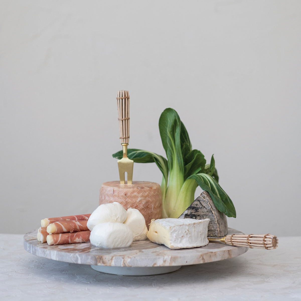The CREATIVE COOP MARBLE LAZY SUSAN features a round, flat design with light brown and beige veining, displayed on a white background. Its slightly raised base creates an elegant elevated look—perfect as a kitchen centerpiece for entertaining.