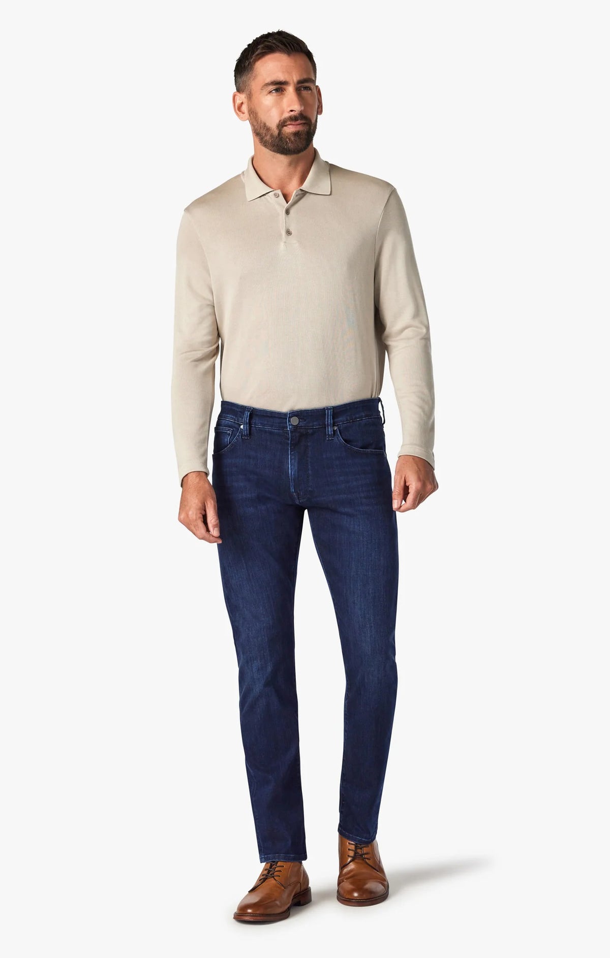 A man stands with his back to the camera, wearing a beige long-sleeve shirt, 34 HERITAGE - COURAGE STRAIGHT LEG JEAN IN DARK MIDNIGHT BRUSHED URBAN WASH, and brown shoes against a plain white background.