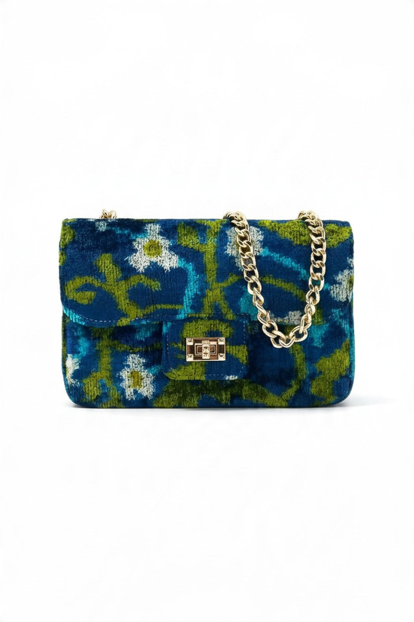 BALDIZ BROOKE CLUTCH VROSSBODY in blue and green floral-patterned silk velvet with a gold-tone turn-lock clasp and a matching gold chain shoulder strap.