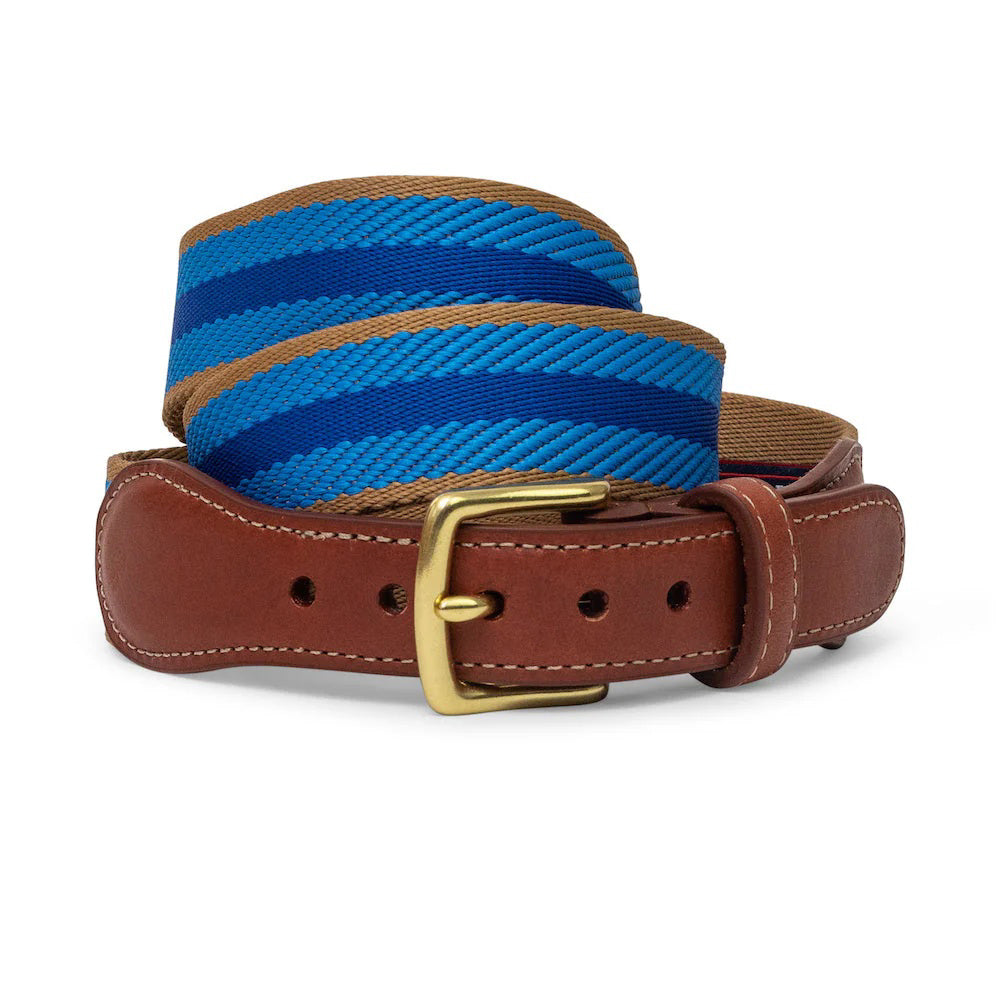 The COLLARED GREENS Dockside Belt by Bird Dog Bay features a brown leather buckle section, gold buckle, and navy strap with light blue and tan stripes. Both leather and fabric are coiled. Proudly crafted in the USA.