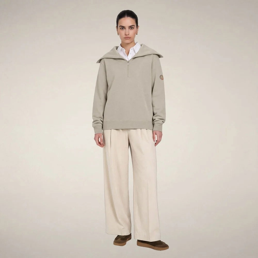 A woman wears a sleek rainy beige SAVE THE DUCK - HINATA HALF ZIP TOP with a wide collar and matching wide-leg drawstring sweatpants.