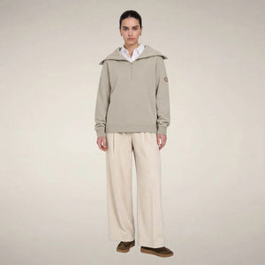 A woman wears a sleek rainy beige SAVE THE DUCK - HINATA HALF ZIP TOP with a wide collar and matching wide-leg drawstring sweatpants.