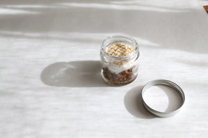 A small glass jar with a white lid labeled "MADISON GREEN - WHILE DRIVING STRESS RELIEF AROMATHERAPY INHALER," featuring a blend of organic essential oils and botanicals for stress relief, set against a plain white background.