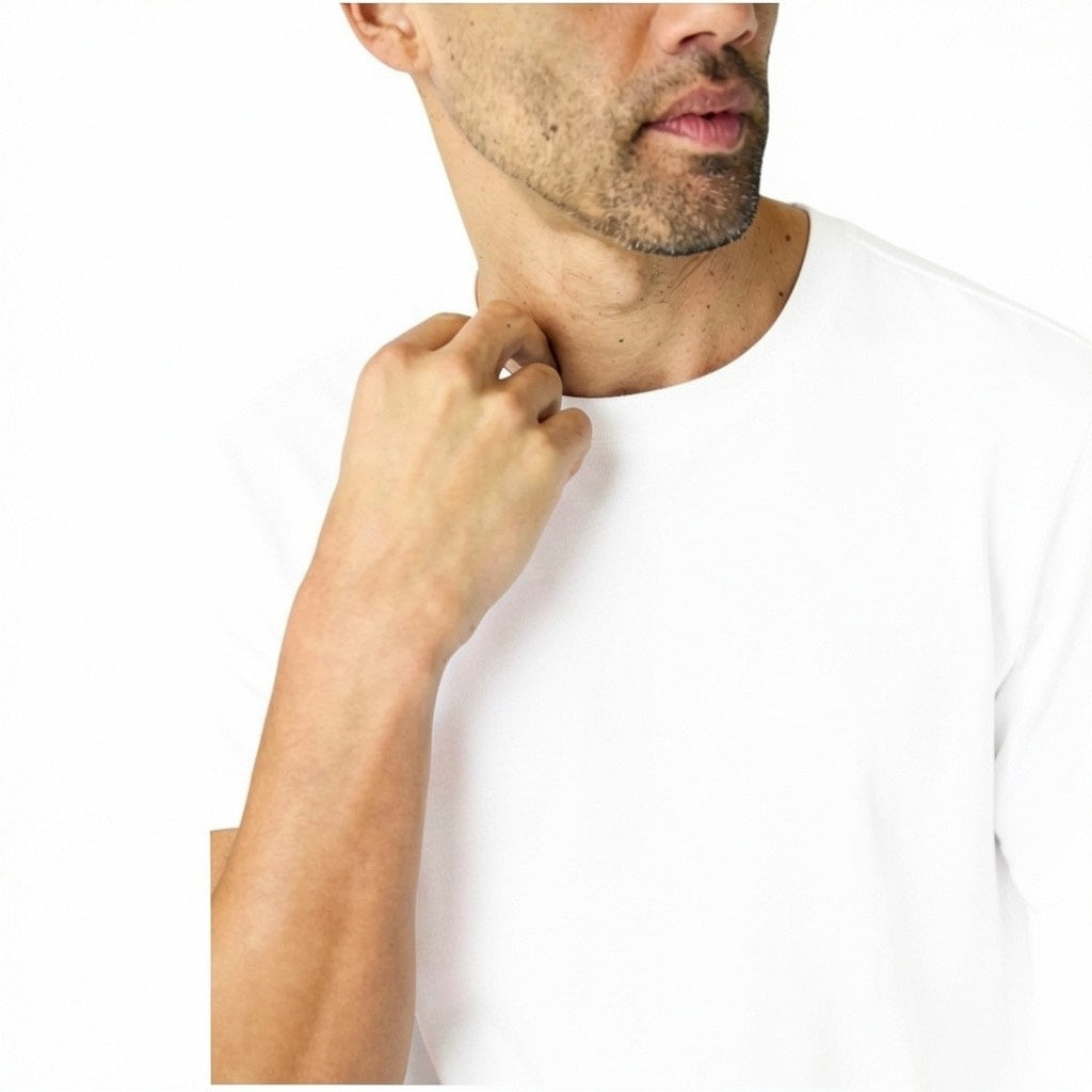 A man with short hair and light stubble wears the MACK WELDON Slub Cotton Crew Neck T-Shirt in Bright White, paired with dark pants, standing against a white background and looking slightly to his left.