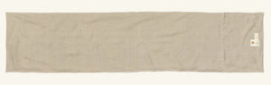 A CHRISTMAS CHEER EMBROIDERED LINEN TABLE RUNNER featuring woodland animals in winter attire and Christmas trees, draped over a wooden dining table set with plates, glassware, and candlesticks.