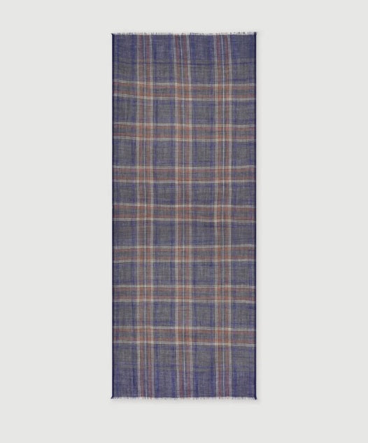 A man wearing a grey long-sleeve sweater and the HARTFORD - TARTAN WOOL SCARF IN INDIGO, GREY AND CAMEL stands against a white background, looking directly at the camera with his hands in his pockets—showcasing this classic men’s winter accessory from HARTFORD.