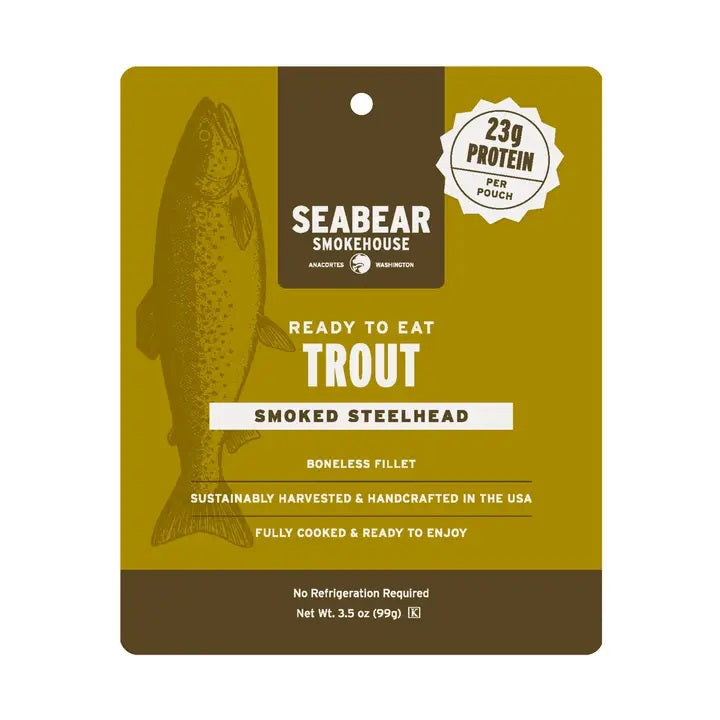 A gold pouch of SEABEAR SMOKEHOUSE Searbear Smokehouse Ready-To-Eat Smoked Trout features premium portable trout fillets made from Idaho trout, with each 99g pouch providing 23g of protein. The packaging displays a fish illustration and product details in white and yellow text.