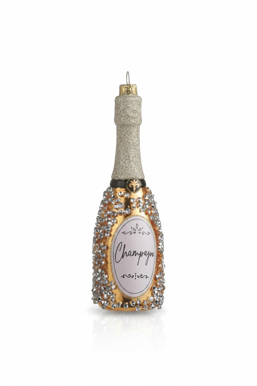 CHAMPAGNE BOTTLE ORNAMENT by RAZ IMPORTS measuring 6.25 inches tall, featuring a gold bottle with a silver glitter neck, decorative silver stones, and a label that says “Champagne.”