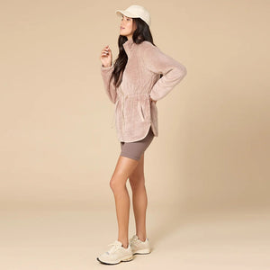 A woman wearing a cream SOFTIES - DREAMPLUSH DOUBLE ZIP JACKET / TUNIC with a cinched waist, paired with wide-leg denim culottes for cozy velvety softness.