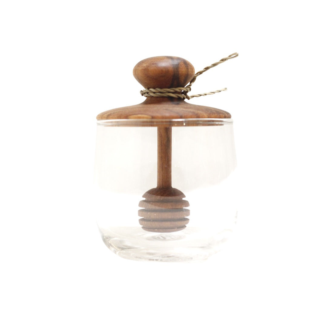The BE HOME, INC MINI TEAK GLASS HONEY JAR features a clear glass design with a wooden lid and dipper—ideal for serving honey at tea parties or adding style to your home décor.